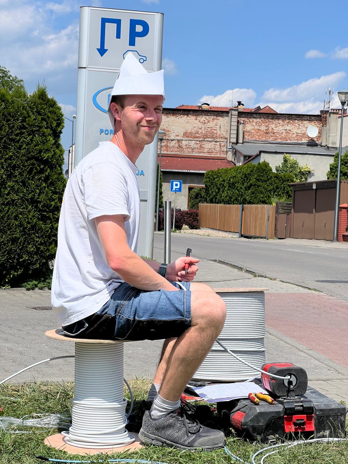 Papierowa czapka i bęben kabla zamiast krzesła — przerwa w terenie